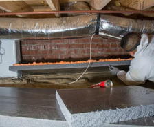 crew member installs crawl space insulation on walls in a crawl space