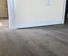 Close-up of a partially installed door, slightly ajar, with a visible green laser line on the hardwood floor—perfect for aligning steps if you're wondering how to fix sagging floors.