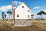 Illustration of a house with severe foundation cracks and tilting chimney, showing subsidence issues.