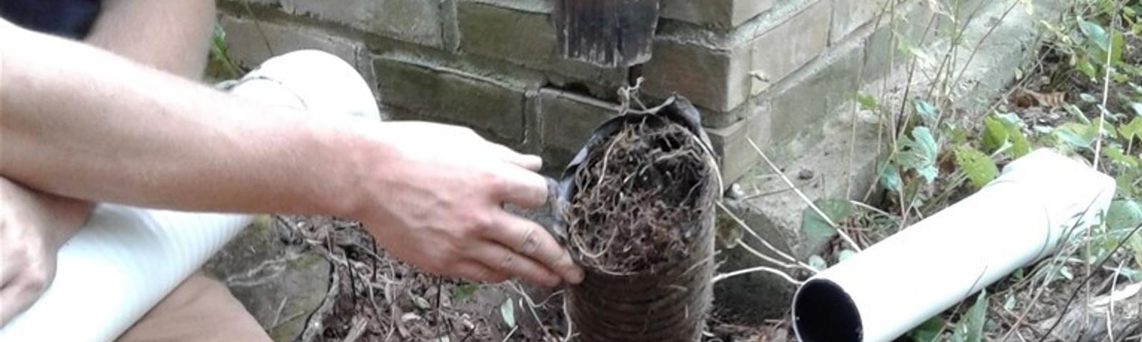 JES Repair inspector assessing clogged drainage on house exterior