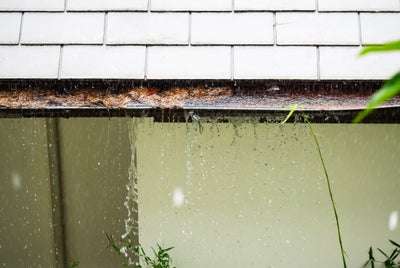 rain falling on house and water spilling out of gutter