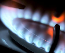 Close-up of a lit gas stove burner with blue flames and an orange glow.