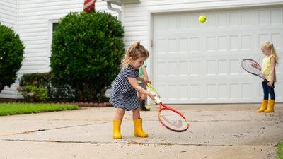 children playing in driveway with bushes in the background