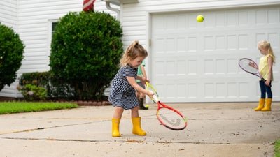 children playing in driveway with bushes in the background