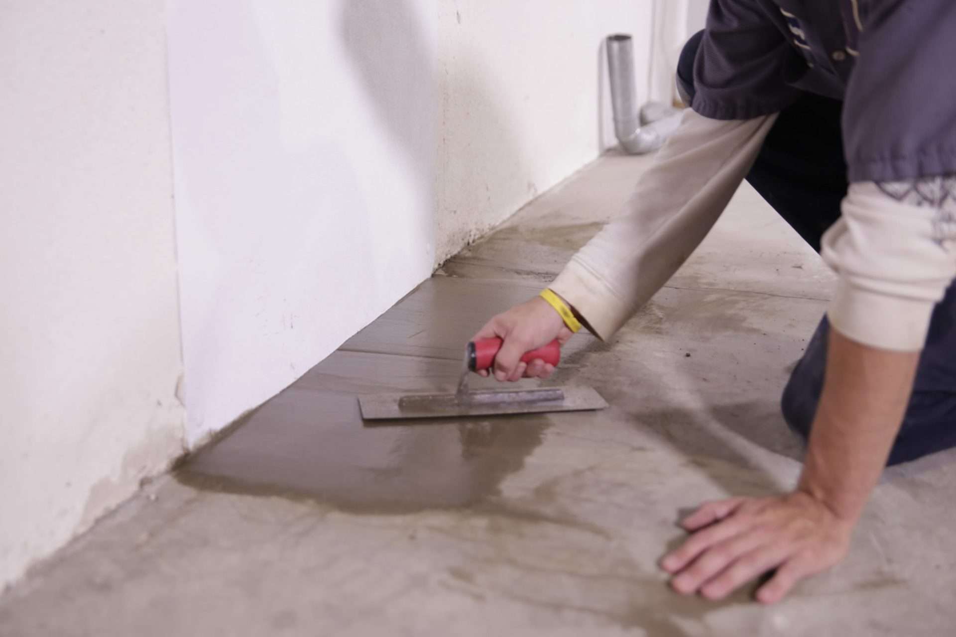 Crew waterproofing basement floors.