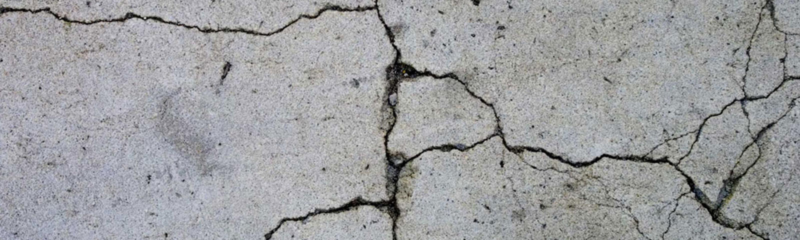 Close-up of cracked concrete floor with visible lines and uneven texture.