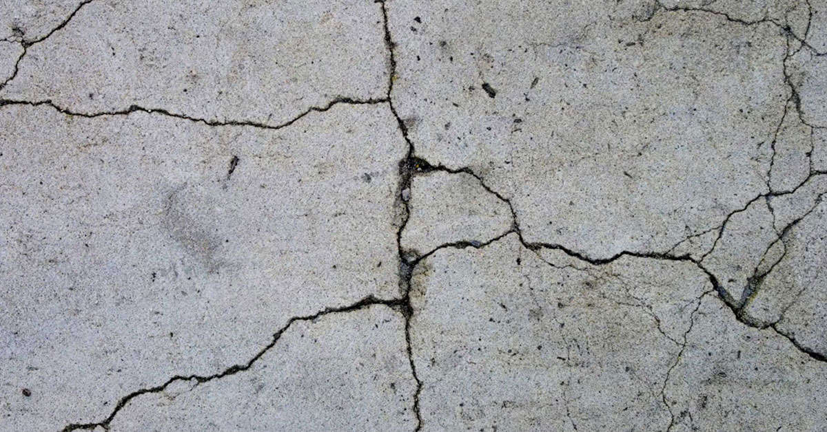 Close-up of cracked concrete floor with visible lines and uneven texture.