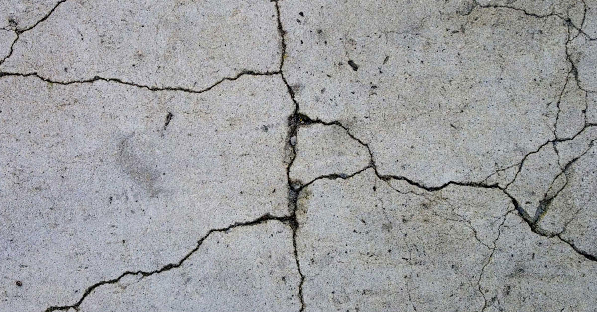 Close-up of cracked concrete floor with visible lines and uneven texture.