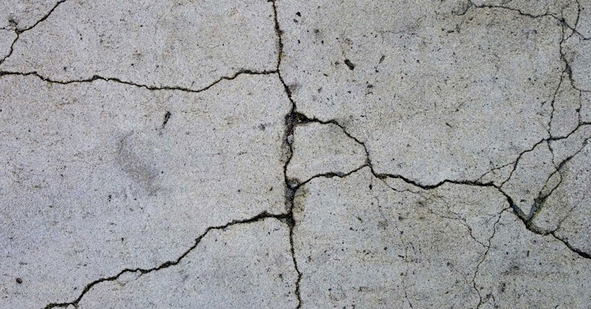 Close-up of cracked concrete floor with visible lines and uneven texture.