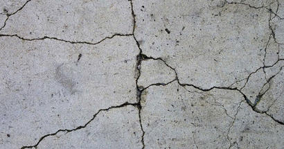 Close-up of cracked concrete floor with visible lines and uneven texture.