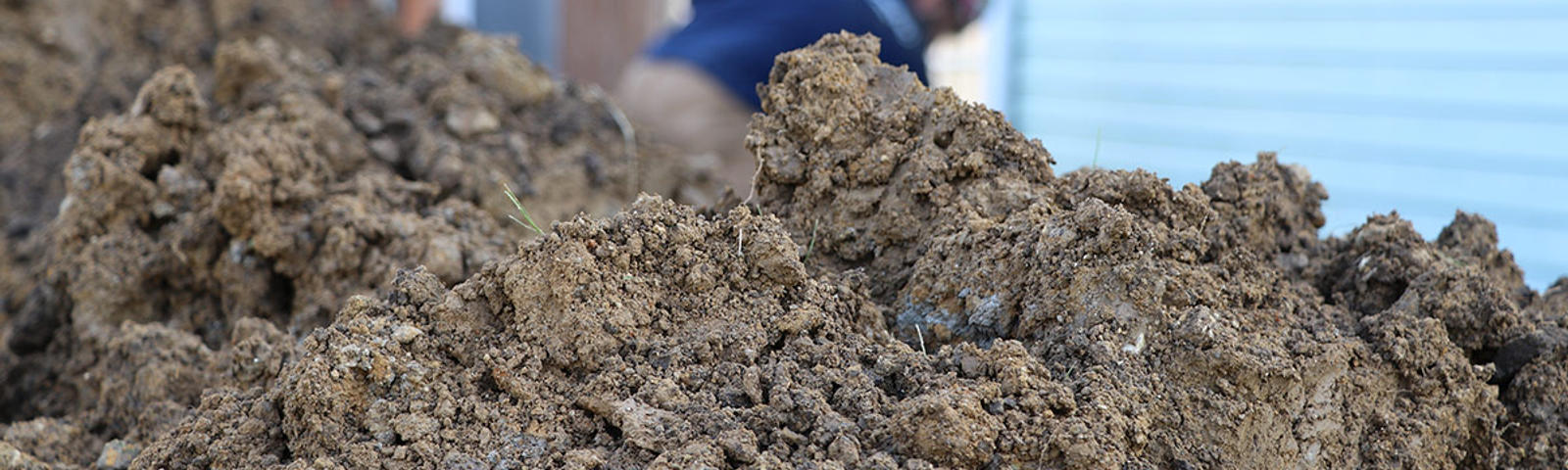 A mound of soil and a crewmember working in the background.