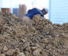 A mound of soil and a crewmember working in the background.