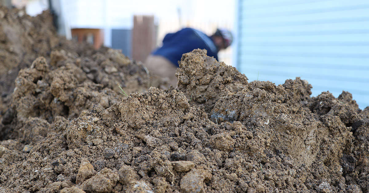 A mound of soil and a crewmember working in the background.