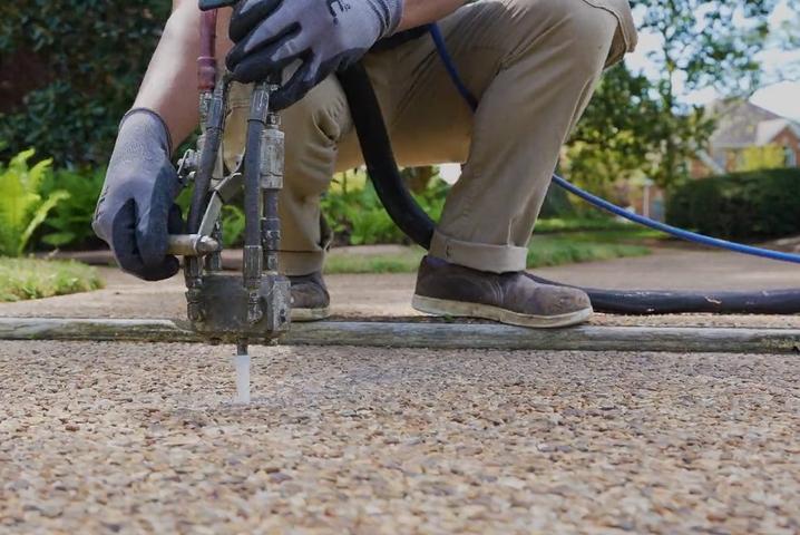 JES Foundation Repair crew injecting PolyRenewal polyurethane concrete lifting foam into a residential walkway.