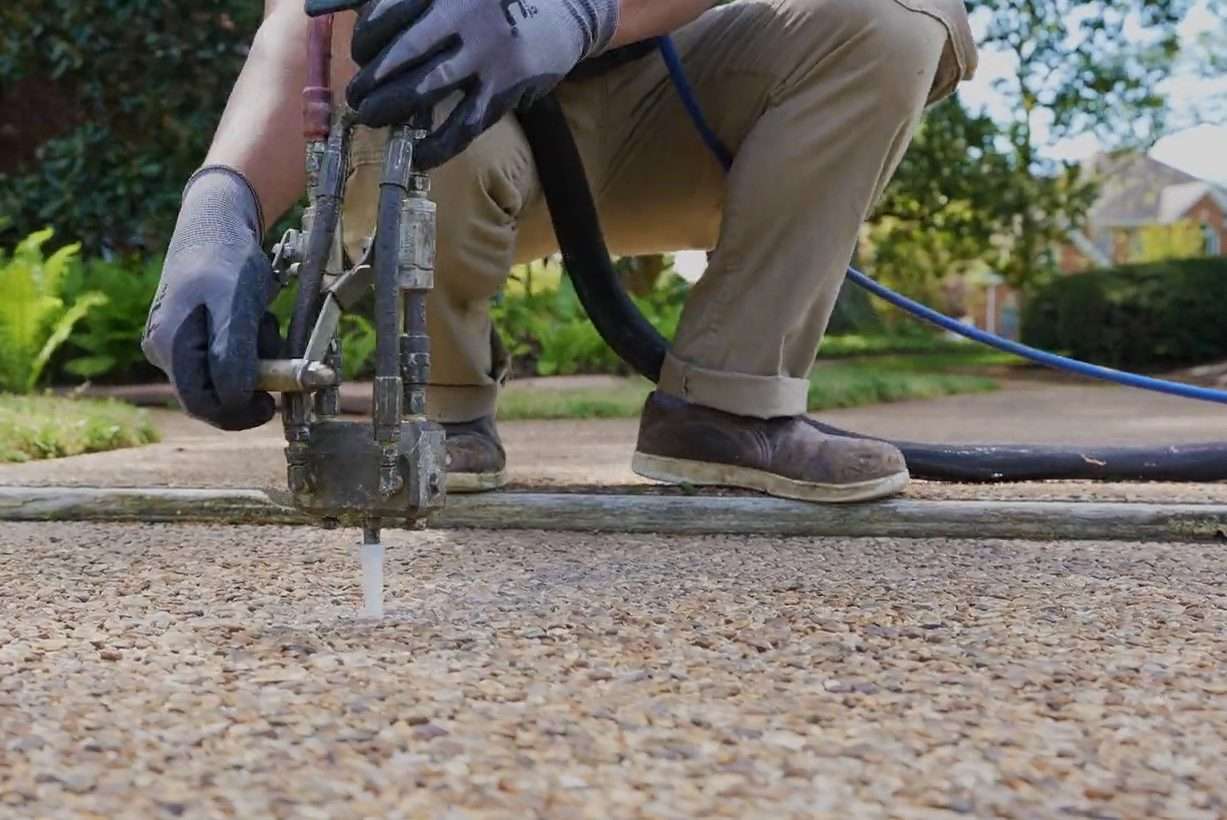 JES Foundation Repair crew injecting PolyRenewal polyurethane concrete lifting foam into a residential walkway.