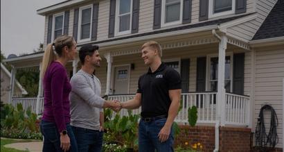 JES Foundation Repair inspector shaking hands with homeowners in front of house