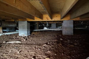 Dirty crawl space with dirt floor and cinder block beams before encapsulation