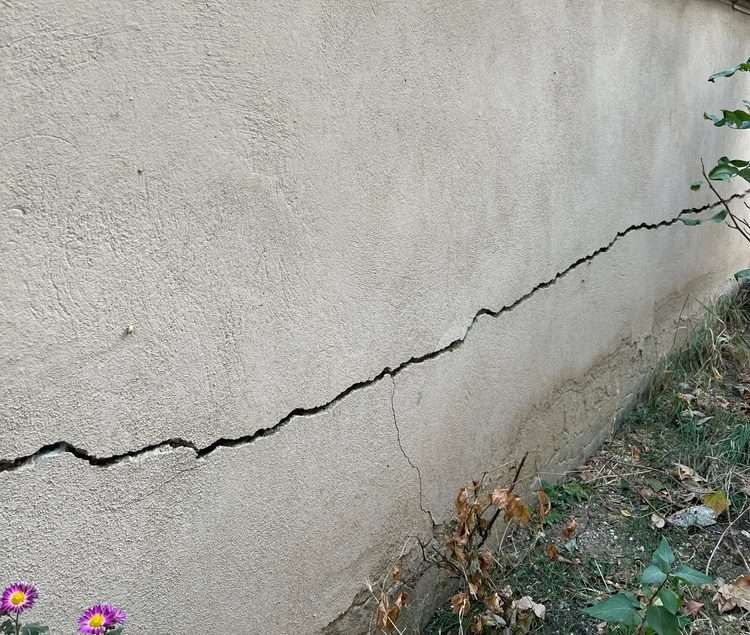 cracked retaining wall with iron railing