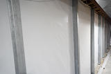 steel wall braces reinforcing a basement wall covered by a vapor barrier