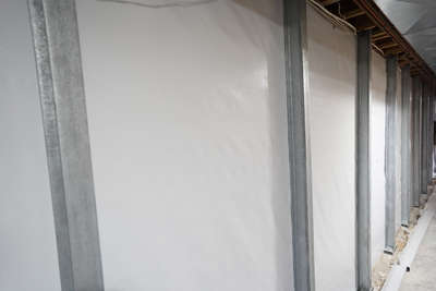 steel wall braces reinforcing a basement wall covered by a vapor barrier