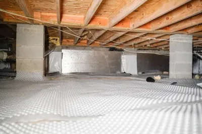 Crawl space encapsulation is evident with a vapor barrier on the floor, complemented by exposed beams above and sturdy concrete support pillars for added stability.