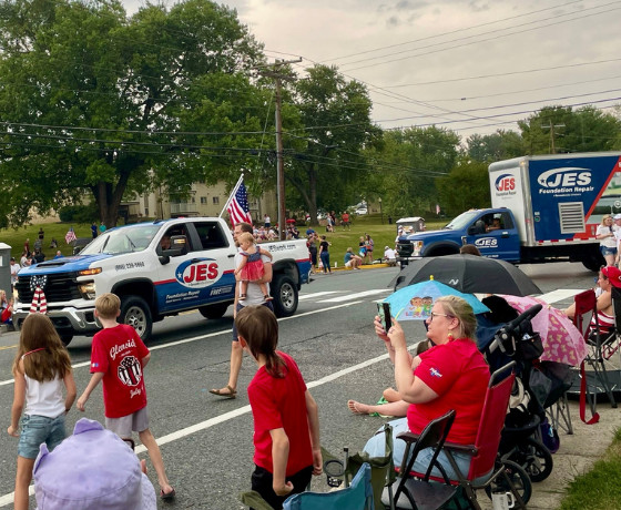 JES employees drive trucks past a crowd of people during the Annual Bel Air 4th of July Celebration parade