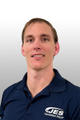 Man in a navy polo with "JES Foundation Repair" logo, smiling against a gray gradient background.