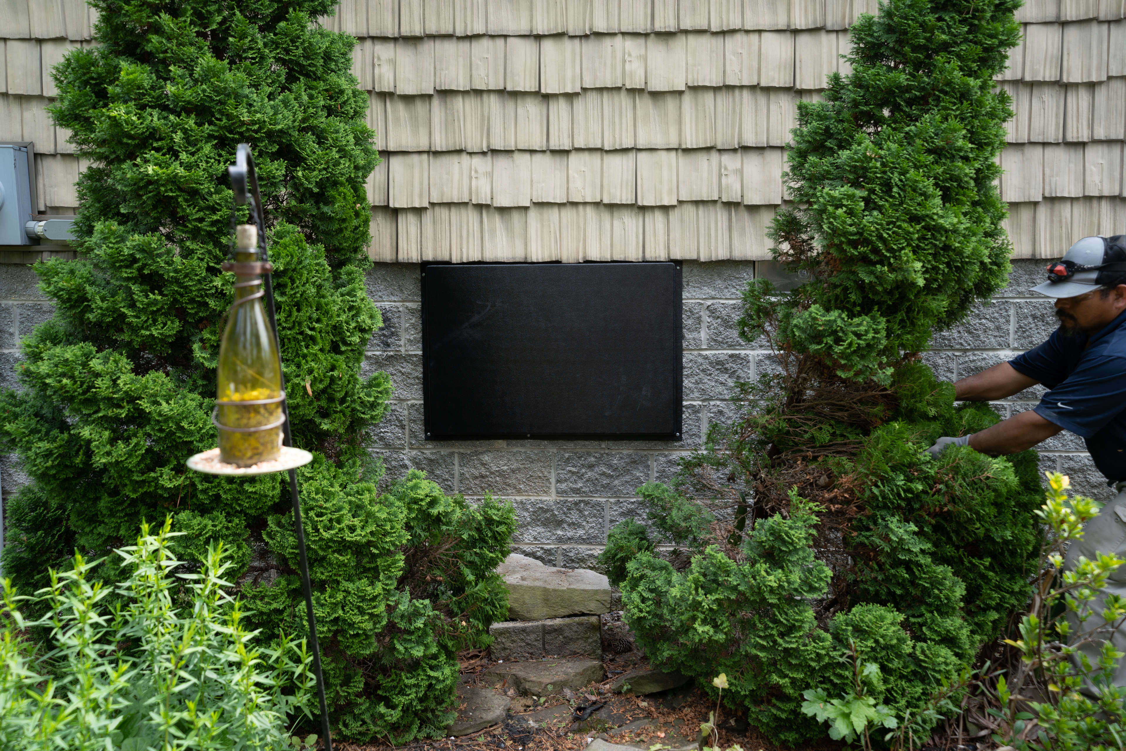 crawl space door on the side of a brick house with bushes