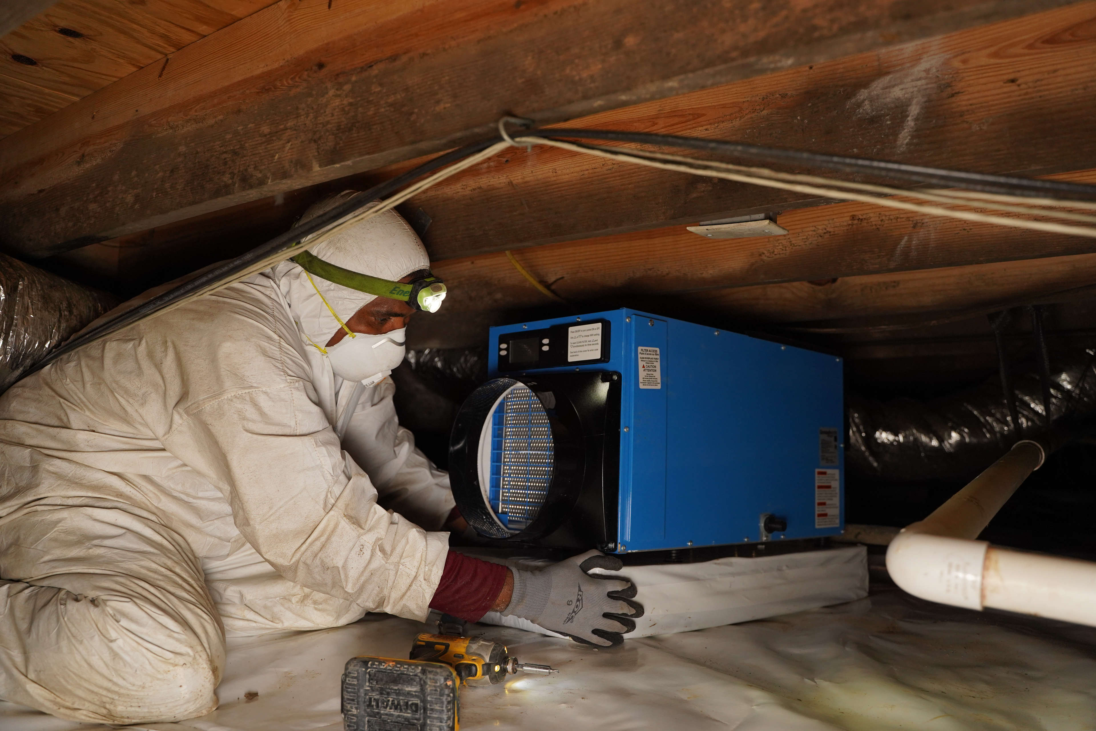 crew member installing a dehumidifier in an encapsulated crawl space