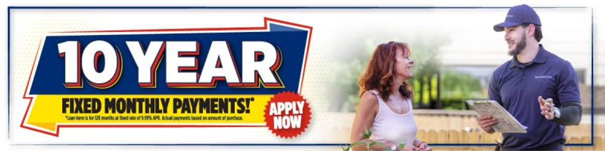 Banner reads "10 Year Fixed Monthly Payments* Apply Now"; a smiling woman talks to a man holding a clipboard.
