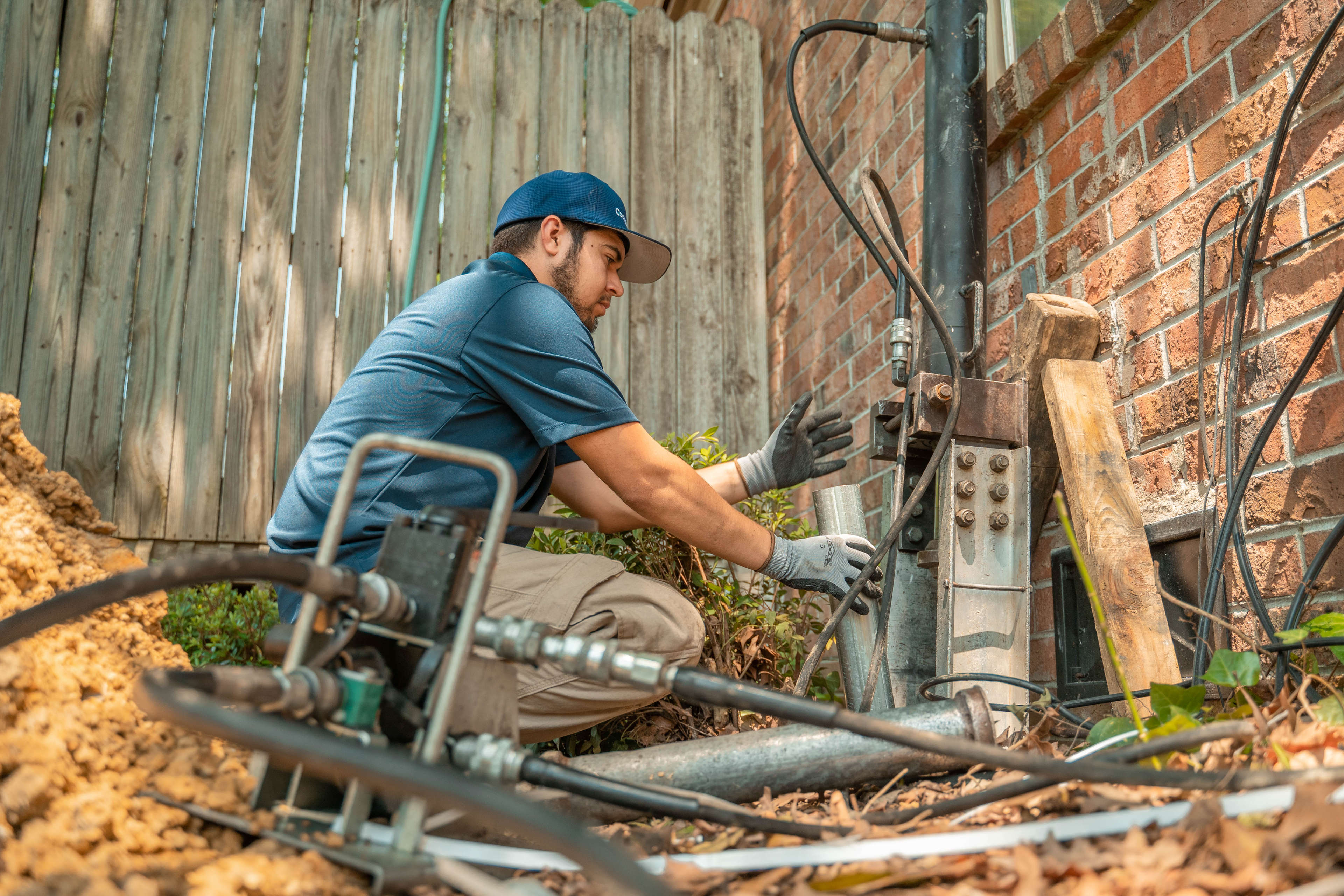 crew member using equipment to install foundation push piers