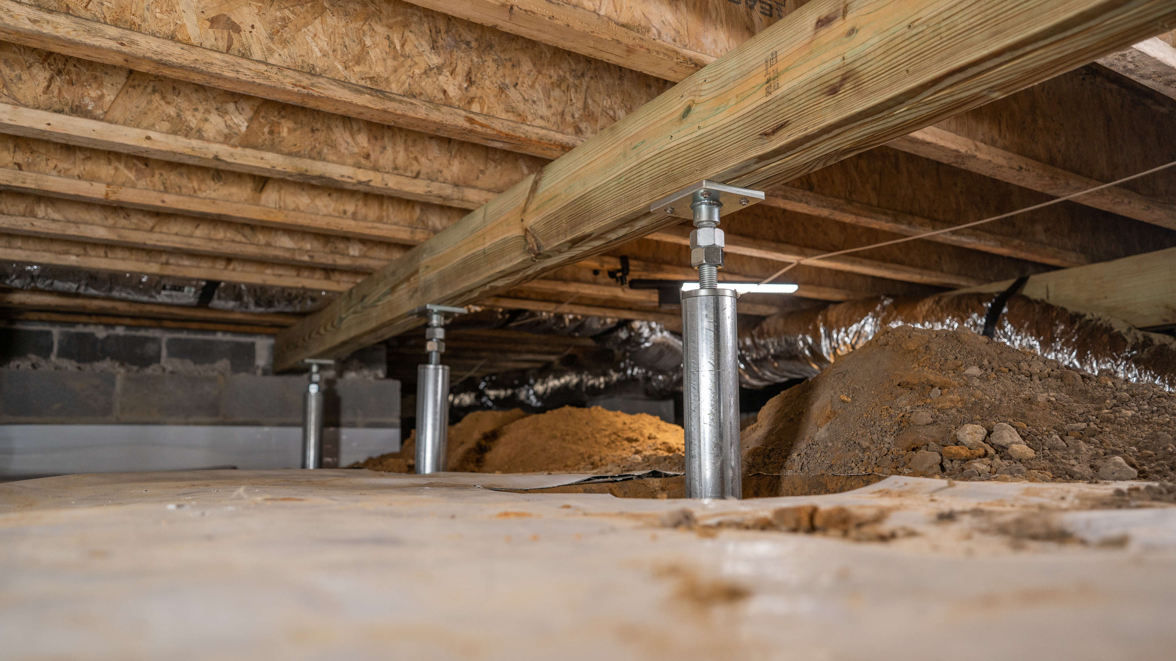 IntelliJack™ support jacks installed beneath a beam in a crawl space