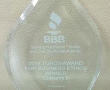 Glass award with "2016 Torch Award for Business Ethics, Winner, Category II" engraved on it.
