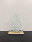 Glass award for "Excellence in Marketing" with a wooden base on a black surface.