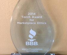 Glass award inscribed with "2014 Torch Award for Marketplace Ethics" from BBB, given to Alpha Foundation Specialists.