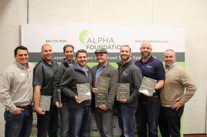Seven men holding awards pose in front of an "Alpha Foundations" banner.