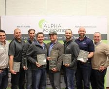 Seven men holding awards pose in front of an "Alpha Foundations" banner.