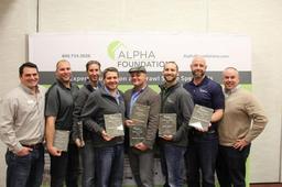 Seven men holding awards pose in front of an "Alpha Foundations" banner.