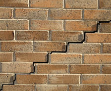 A brick wall with a jagged crack running diagonally through the middle.