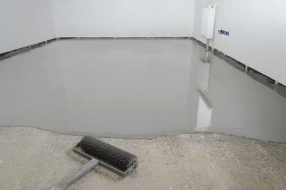 Self-leveling concrete being poured to repair garage floor.