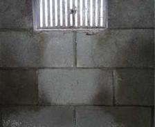Cinder block wall with a vent, insulation on the floor beneath.