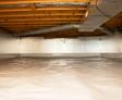 A clean, insulated attic with wooden beams, ducts, and a reflective foil on the walls and ceiling.