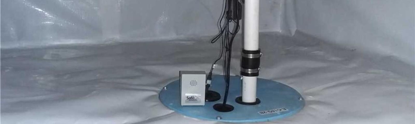 Sump pump system in a basement with white waterproof lining and wiring.