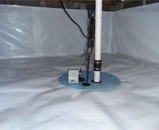 Sump pump system in a basement with white waterproof lining and wiring.