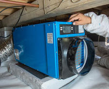 Alpha crew member installing dehumidifier in crawl space.,