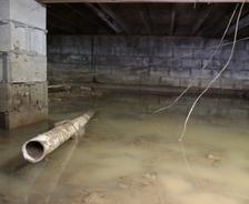 The basement, with standing water, exposed concrete walls, and visible pipes, hints at possible flooding or water damage similar to a flooded crawl space.