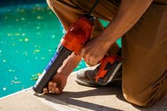 Crew member injecting caulk into a crack in concrete pool deck after poly has been injected.