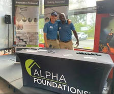 Two people at an Alpha Foundations booth, smiling and posing for the camera.
