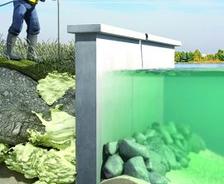Worker applies foam to soil near a retaining wall by water, showing erosion control and wall stabilization.