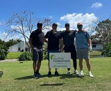 four members of Alpha Foundation's Miami team stand by a company sponsorship sign at the Wellington Wolves' 2nd Annual Basketball Charity Golf Tournament